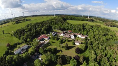 Panoramablick auf eine grüne Landschaft mit Windrädern und einer Siedlung
