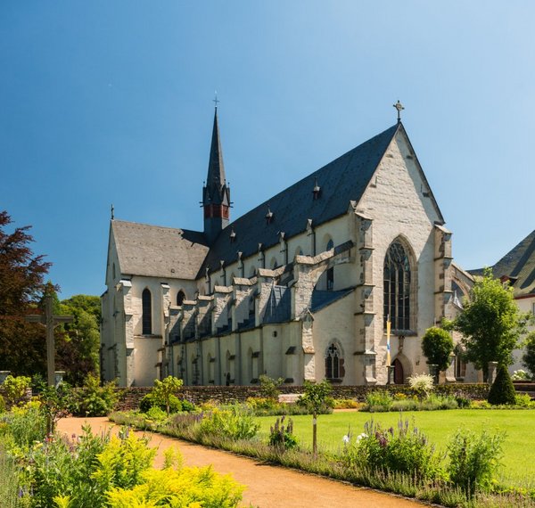 Friedlicher Garten mit bunten Blumen vor einer Kirche