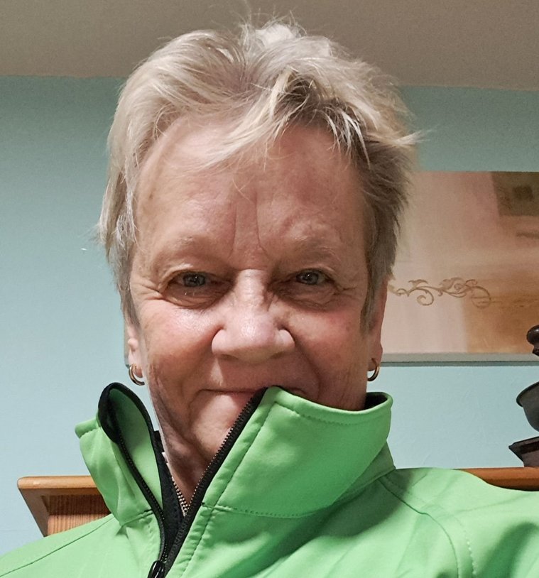 Silvia Patt mit grüner Jacke, die ihren Namen und Titel zeigt.