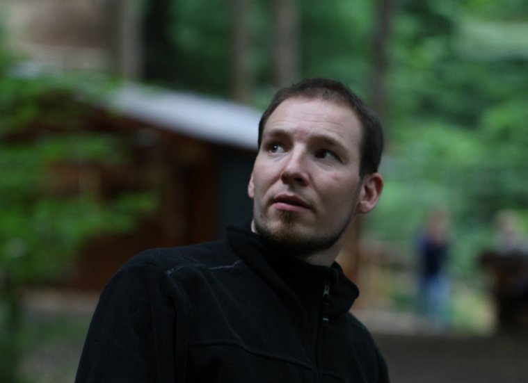 Mann in Jacke steht in der Natur, Blick nachdenklich